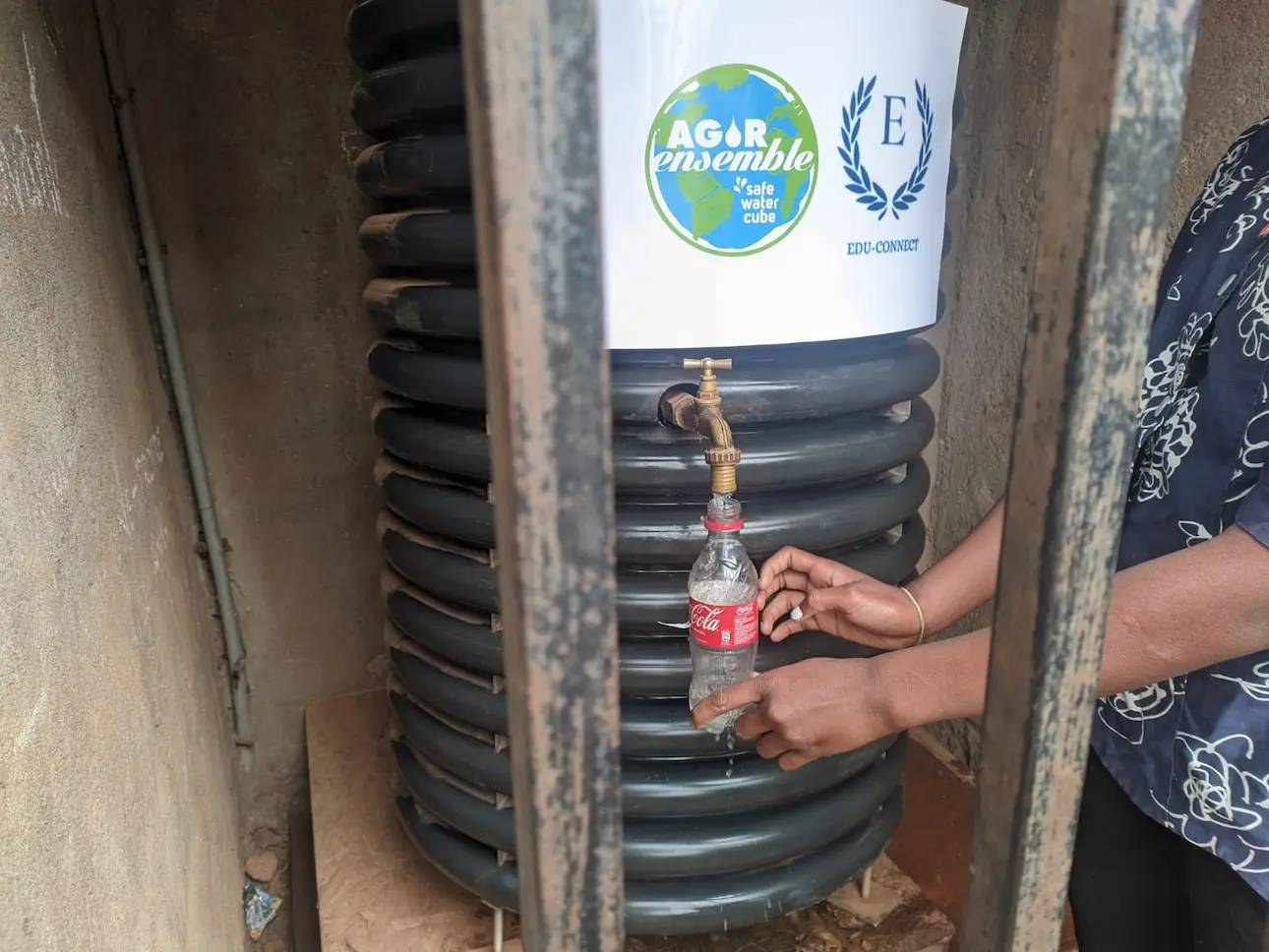 Personne remplissant une bouteille à une borne-fontaine publique.