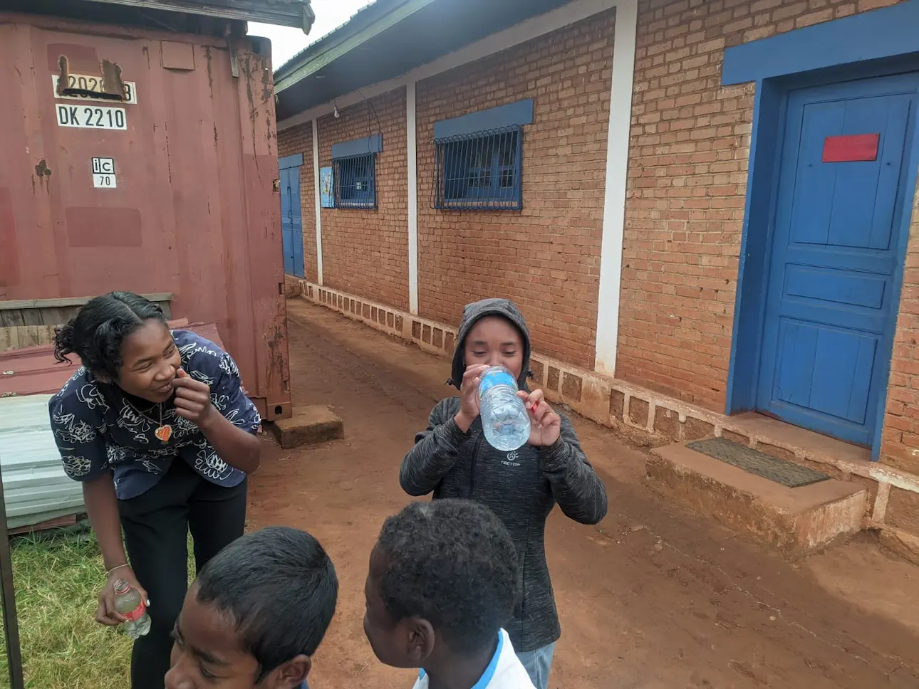 Des enfants jouent dehors près d'un bâtiment en briques.