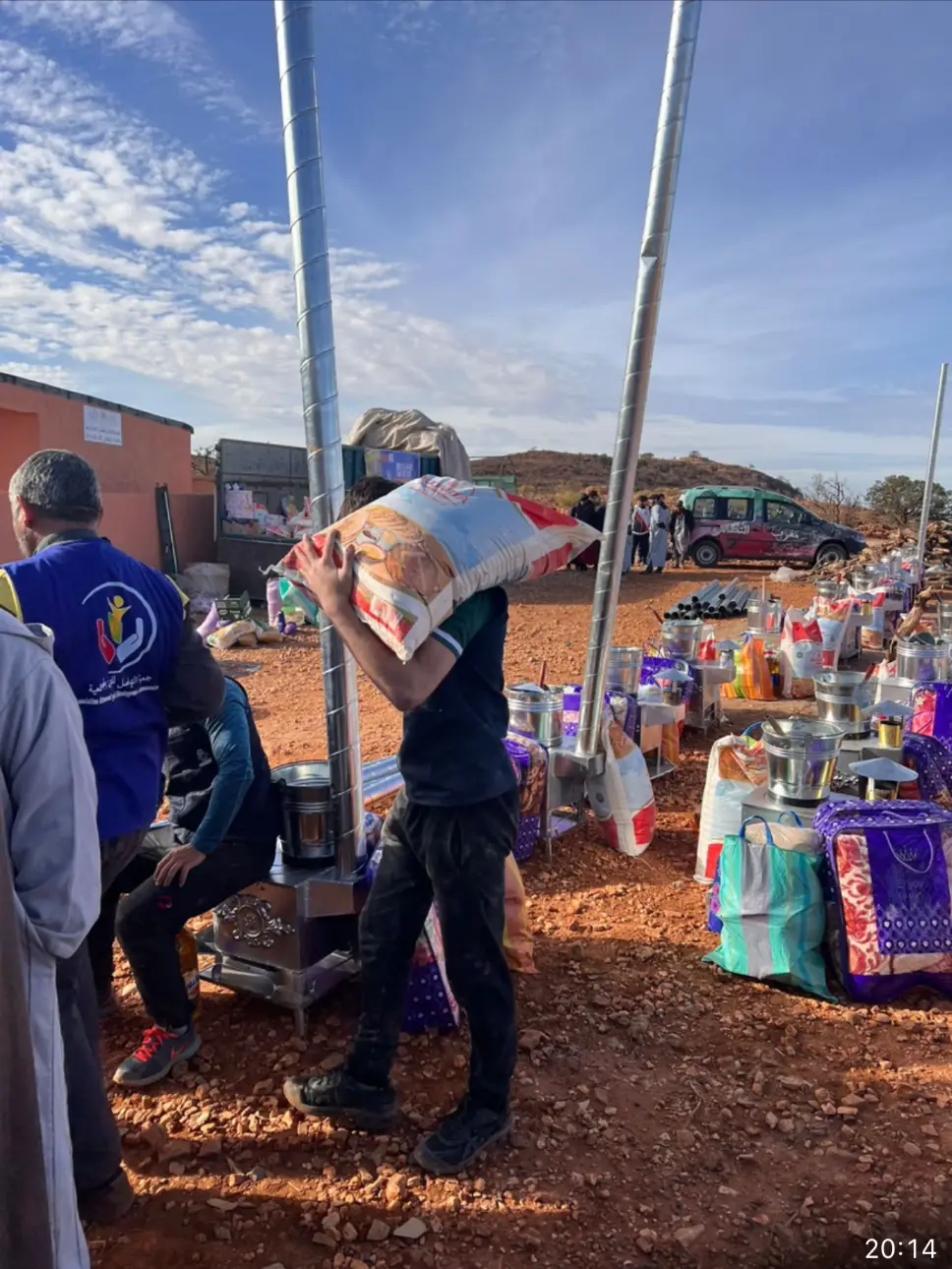 Person carrying food bag at outdoor distribution event.