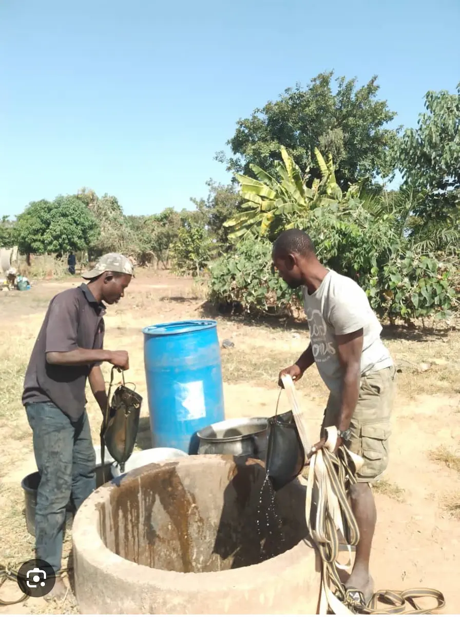 Deux hommes puisant de l'eau dans un puits.