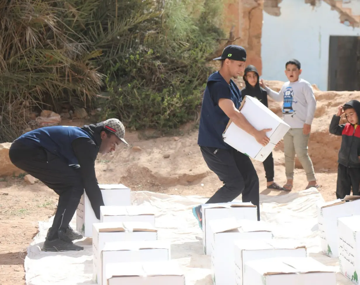 Des personnes distribuent des boîtes aux enfants à l'extérieur.