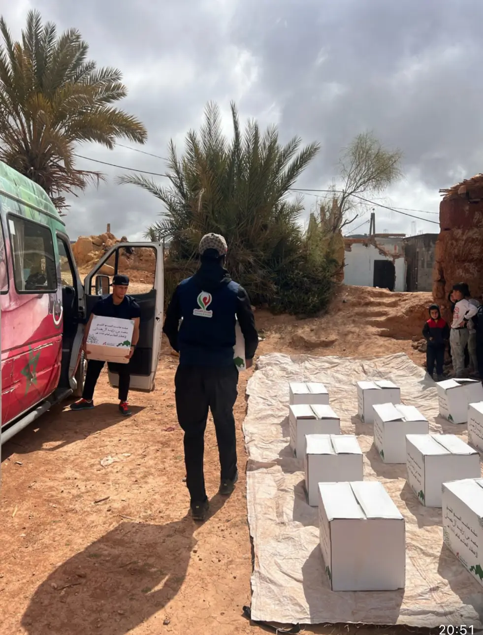 Volunteers delivering aid boxes from van in desert.
