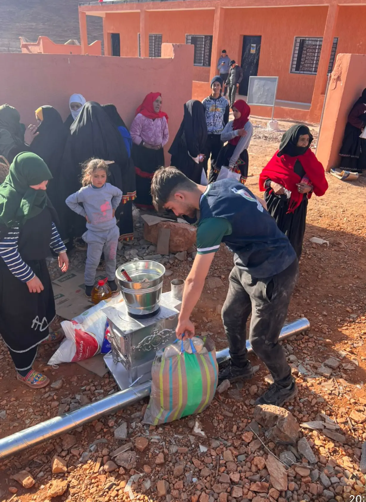 Group gathering outdoors with supplies and cooking.